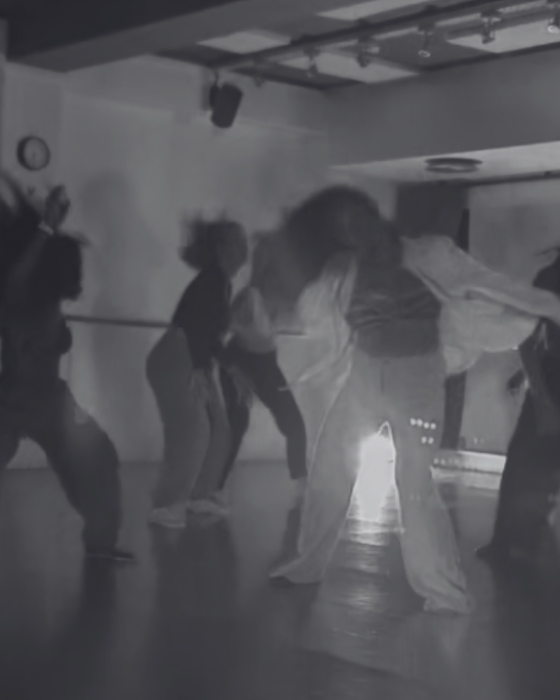 Un groupe de participantes en pleine danse pendant un atelier, en noir et blanc